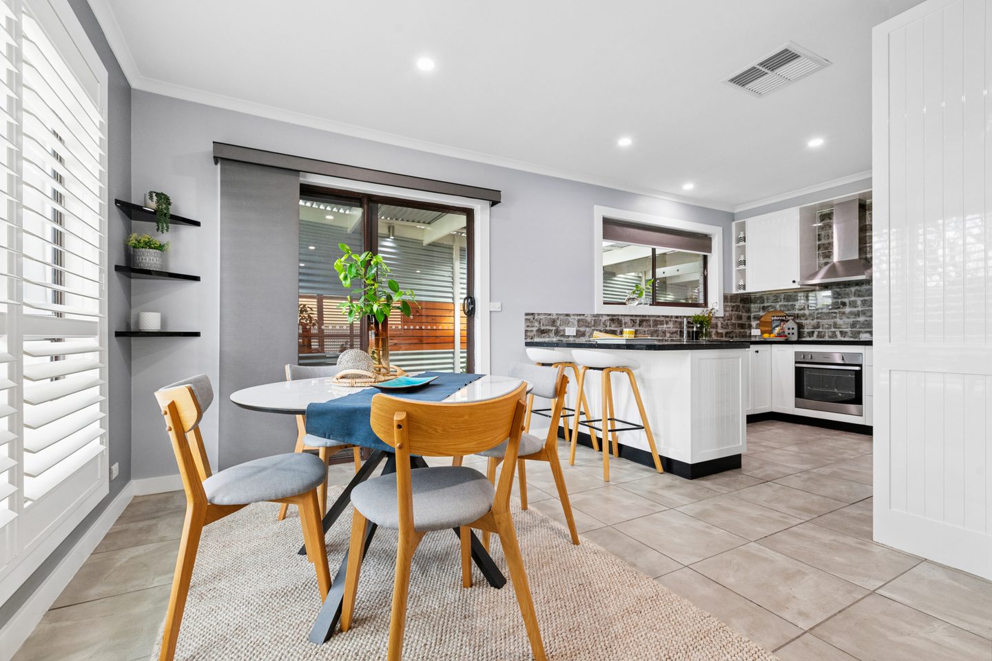 White kitchen and adjoining dining area with a sliding door to the covered patio