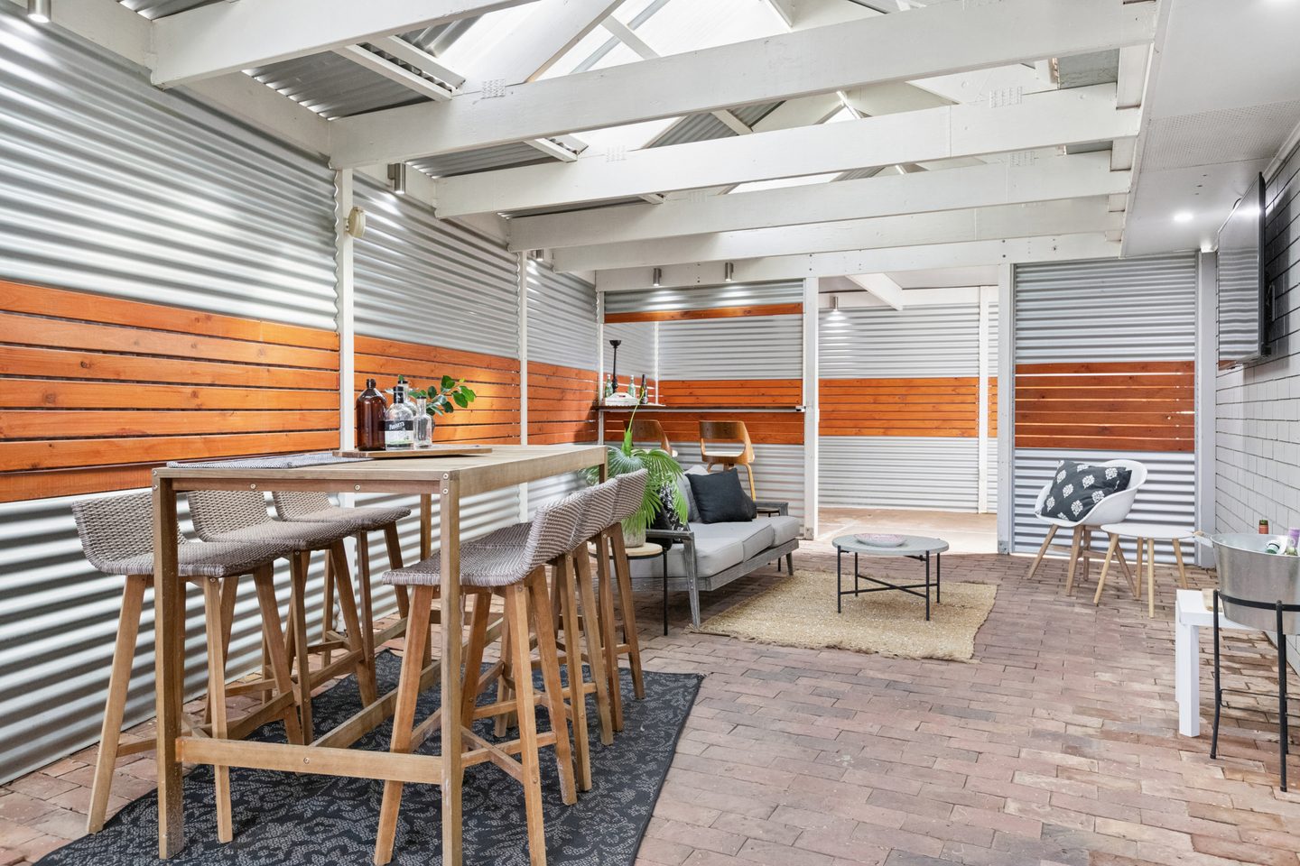 Long covered patio with brick paving, timber screening and a built-in bar